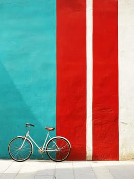 White vintage bicycle against a colorful geometric wall with turquoise and red stripes, creating a striking contrast and artistic urban scene.