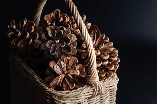 Pine cones in Wicker basket on dark background. Pine cones nice and dry and some are open up, Light and Shadow, use it as your Wallpaper, Poster and Space for text, Selective focus.