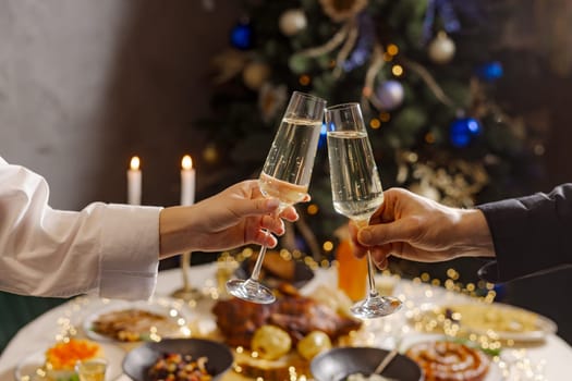 hands with glasses of champagne close-up on the background of a festive Christmas table, concept christmas