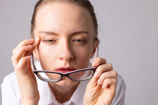 A woman with poor eyesight squints her eye to focus her vision, the concept of optics and choosing glasses