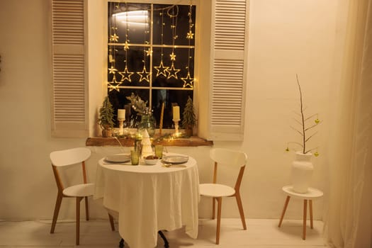 Cozy Christmas setting with a round table near the window, The table is decorated with a decorative Christmas tree in the center, Soft lighting from candles and garlands