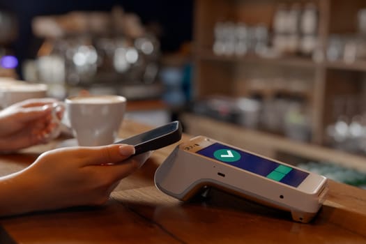 customer makes contactless NFC payment by phone through terminal in cafe, concept successful payment, electronic wallet