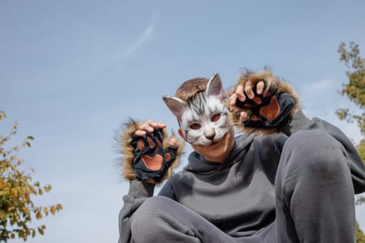 quadrobics teenager in cat mask sits on all fours in park, quadrobika subculture imitation of animal actions