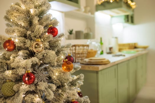 Beautifully decorated Christmas tree with red and gold ornaments, illuminated by warm white lights. In the background is a cozy kitchen with festive decorations, in a warm holiday atmosphere.