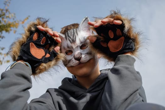 quadrobics teenager in cat mask sits on all fours in park, quadrobika subculture imitation of animal actions
