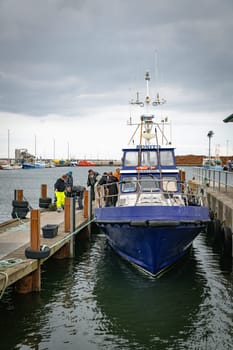 hanstholm,denmark,18-08-2024:Fishing boats are docked at a bustling harbor as fishermen prepare their gear. The scene captures the essence of maritime life and coastal work environments.