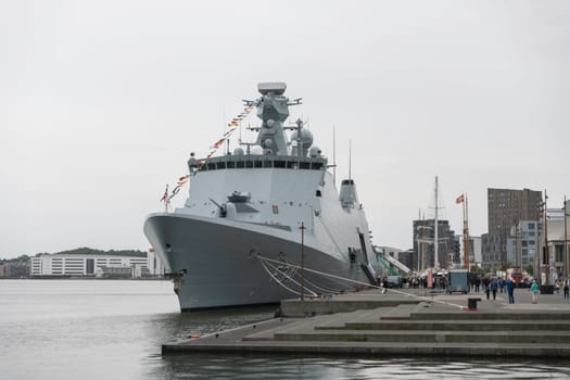 aalborg,denmark,22-08-2024:the f341 war ship denmark in aalborg,naval warship is docked at an urban waterfront, showcasing maritime technology. The harbor scene captures the essence of coastal infrastructure and modern naval presence.