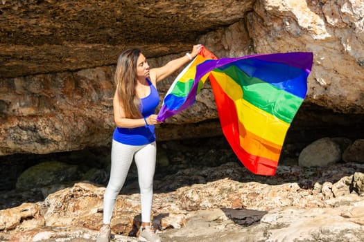woman, middle aged, outdoors waving pride flag, concept of libertat, equality.