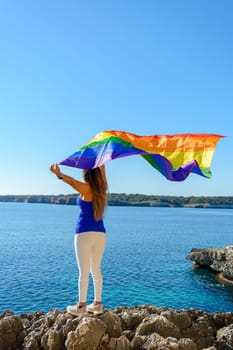 woman, middle aged, outdoors waving pride flag, concept of libertat, equality.