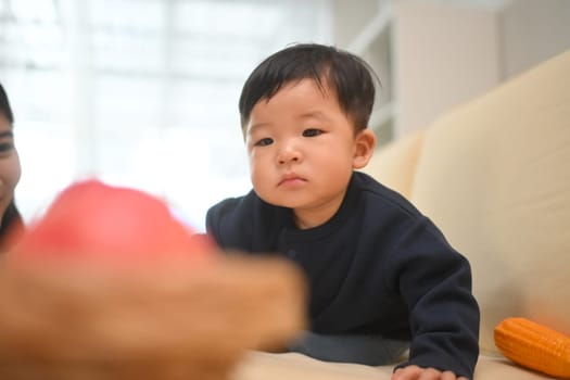 Adorable toddler exploring his surroundings in living room with curious expression. Child care concept.