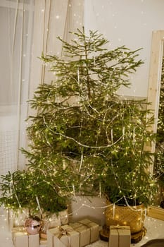 Designer Christmas tree decoration with light decorations. The concept of celebrating New Year and Christmas. Gifts in craft packaging under the Christmas tree.