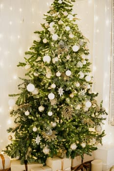 A large Christmas tree in the living room, decorated with garlands and light balloons. Bright Christmas interior