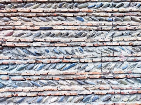 A detailed view of a wall featuring alternating bricks and stones arranged in a unique pattern.
