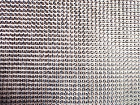 A close-up view of a surface covered with numerous metallic pins arranged in a grid pattern.