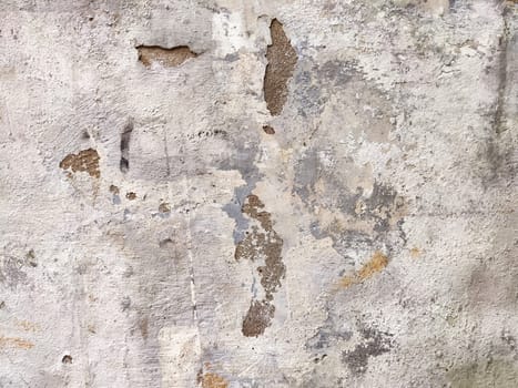 A weathered wall surface displaying a unique texture, showcasing cracks and peeling paint, ideal for backgrounds or design elements.