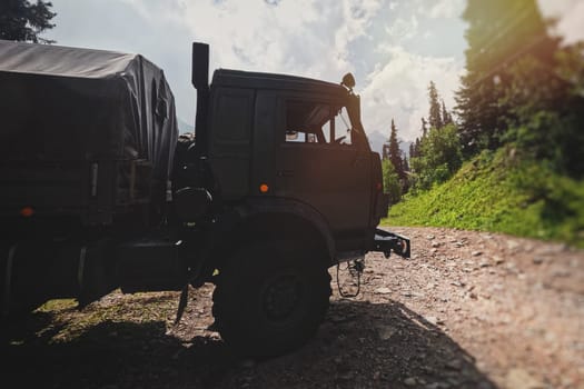 KAMAZ military truck is parked on a rugged and uneven road, surrounded by a scenic and beautiful mountain forest landscape