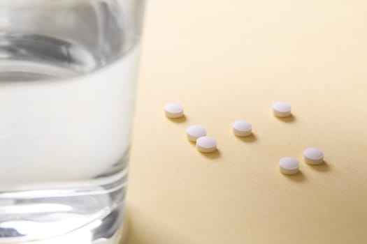 Pills on the table next to a glass of water, copy space.