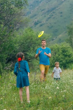 A joyful family is happily playing frisbee together in a sunny and vibrant meadow that is filled with flowers