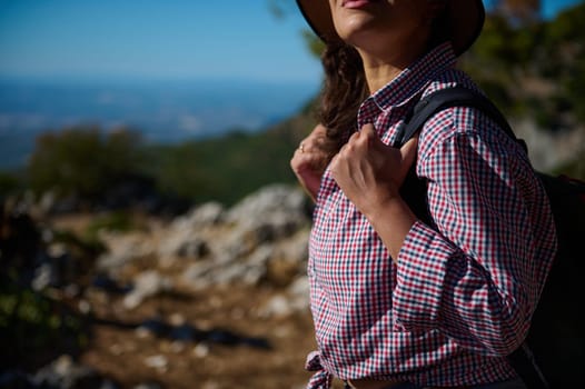 A woman enjoys a hike through a picturesque natural landscape, wearing a checkered shirt and carrying a backpack. The scene evokes adventure and exploration.