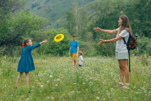 Children enjoy outdoor play, tossing a frisbee in a vibrant green field with mountains in the background.