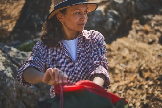 A woman in a plaid shirt enjoying a moment of tranquility during a hike in a sunny, serene natural setting.