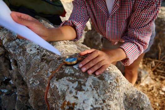 A person navigating with a compass and map on a rocky surface, embodying exploration and adventure. The scene evokes a sense of direction and outdoor discovery in daylight.
