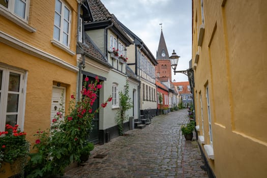 typical street in denmark aalborg with red yellow and blue houses and church