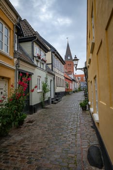 typical street in denmark aalborg with red yellow and blue houses and church