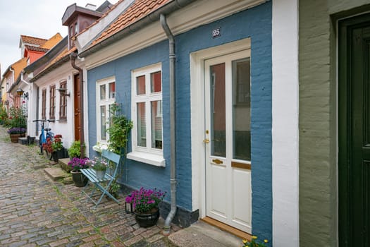 typical street in denmark aalborg with red yellow and blue houses and a bicycle and flowers in pots
