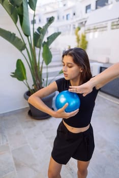 A focused young woman engages in exercise routines with a large blue fitness ball in a stylish indoor environment
