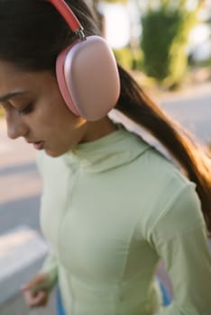 A young woman is wearing trendy headphones while she enjoys listening to music outdoors in the fresh air