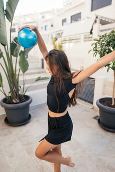 A young woman is joyfully dancing with a bright blue balloon in a colorful and vibrant outdoor atmosphere