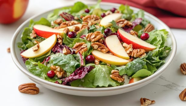 Fresh and colorful salad with apple slices, pecans and cranberries over mixed greens