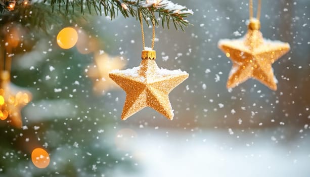 Golden christmas star ornament hanging on a fir tree branch covered in snow with falling snow and bokeh lights in background