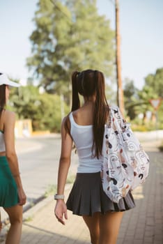 Two fashionable girls are joyously enjoying a sunny day outdoors while capturing a carefree and delightful moment