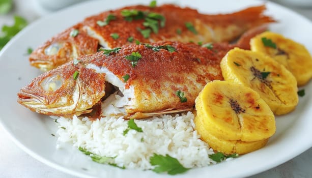 Two fried whole fish seasoned with paprika and parsley are served on a white plate with plantains and rice