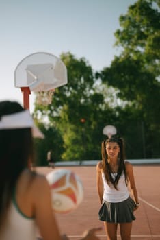 Two enthusiastic girls are having a wonderful time playing volleyball on a bright, sunny outdoor basketball court