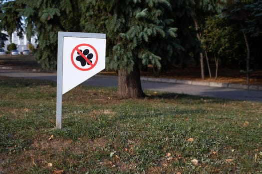 Sign on park lawn prohibiting walking dogs, ban on walking dogs in public place, taking care of cleanliness of pet feces on street, rules for pet owners for walking dogs in city park