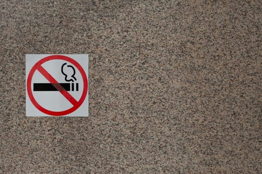 Sign prohibiting smoking in public place on wall of building, smoking ban, sticker indicating smoking free zone, social problem of smoking and fight against bad habits of people