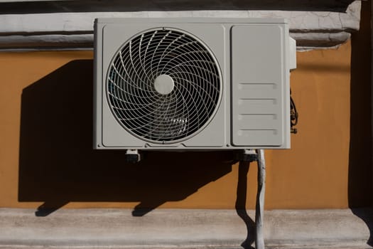 Outdoor air conditioner unit hanging on wall of house, external part of air conditioner to cool temperature in apartment in hot weather, convenience device of modern life