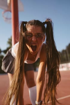An enthusiastic girl with pigtails joyfully expresses her excitement while playing on a colorful basketball court