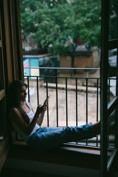 A serene scene depicts a person savoring a tranquil moment while lounging on a cozy balcony using their phone