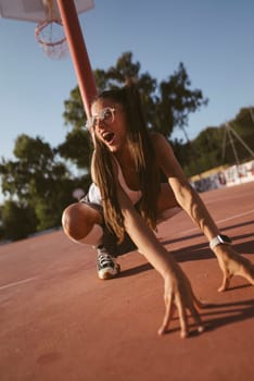 An energetic and enthusiastic athlete is showcasing their creativity by striking a dynamic pose on the basketball court