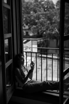 A person sits thoughtfully in a cozy window nook, quietly reflecting and evoking a deep sense of solitude