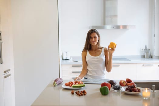 In a brightly lit kitchen, a woman joyfully holds up delicious cheese while surrounded by an array of fresh fruits