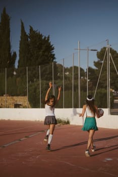 Two friends enjoy a lively moment together on a sunny sports court, capturing their youth and joy outdoors