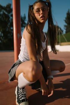 A young girl displays her sporty style and confidence as she enjoys playing on an outdoor basketball court