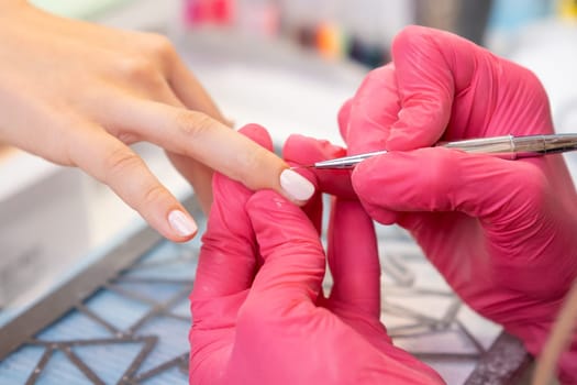 The manicurist uses a small brush to smooth out a layer of gel polish.