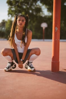 A young female athlete confidently poses on a vibrant basketball court, showcasing her stylish sporty demeanor