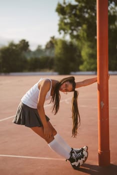 A young woman in sporty attire leans against a post on a sunny court, radiating confidence and positivity